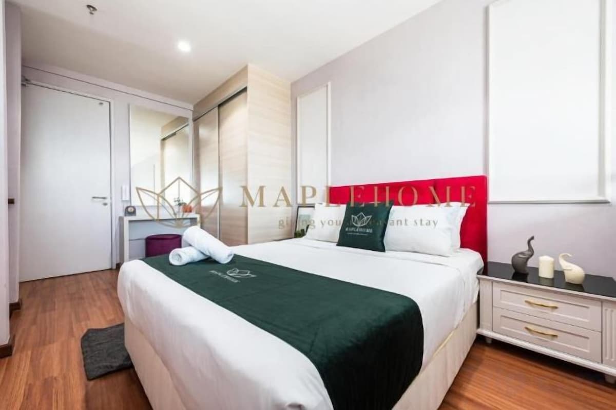 Ein Hotelzimmer mit Bett, Nachttisch, Spiegel, Kleiderschrank und einer roten Akzentwand.