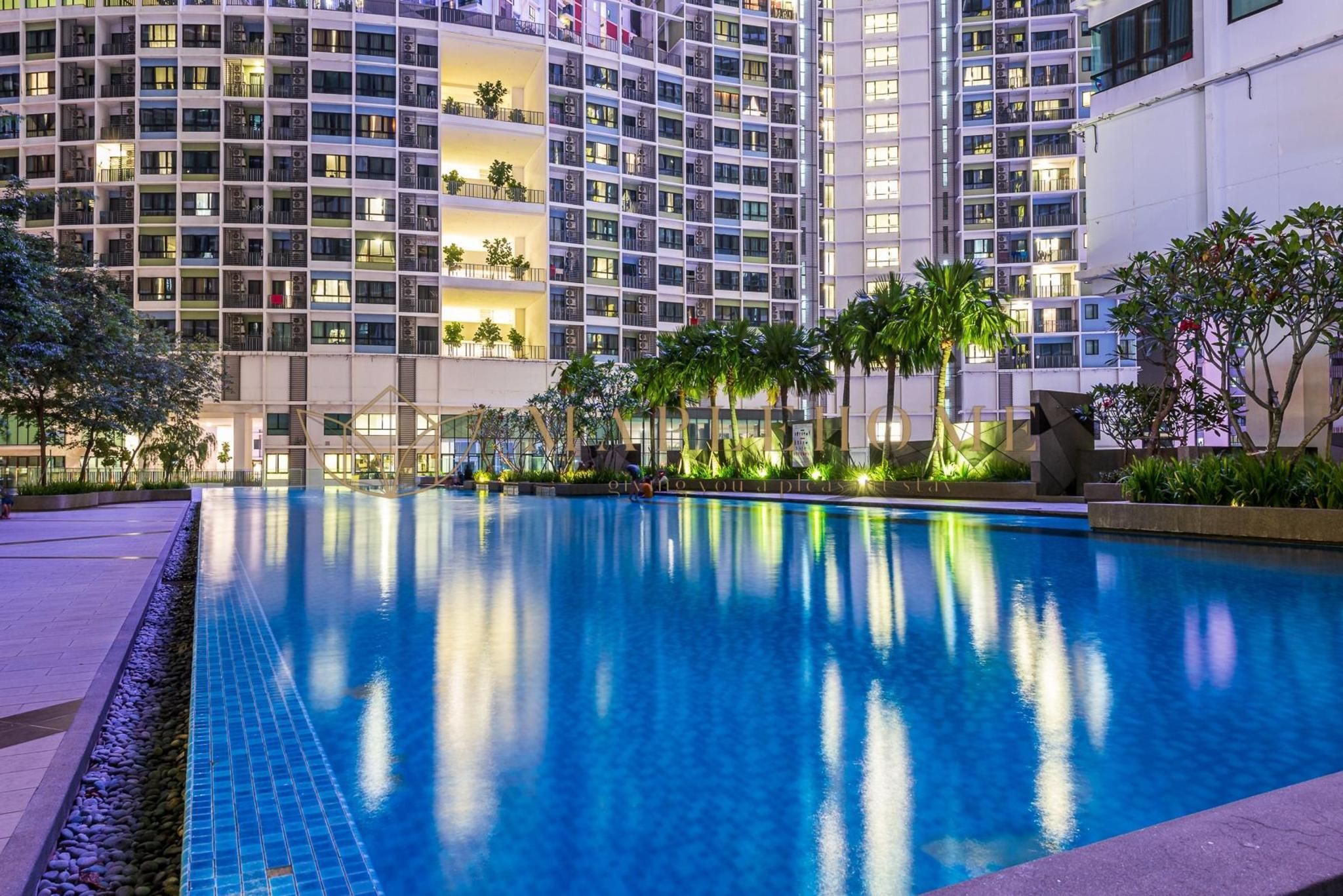 A modern hotel with a large indoor swimming pool surrounded by lush greenery and palm trees.