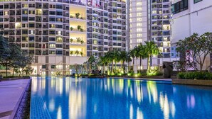 Um hotel moderno com uma grande piscina interior rodeada por vegetação exuberante e palmeiras.