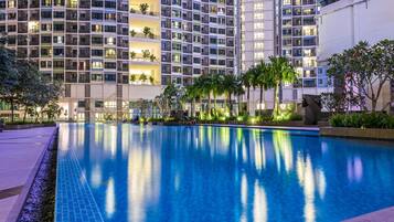 A modern hotel with a large indoor swimming pool surrounded by lush greenery and palm trees.