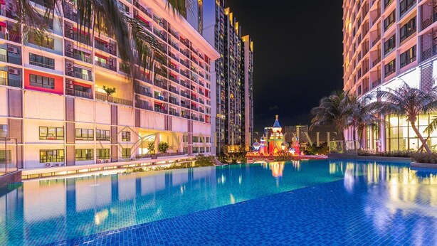 Hotel com piscina, várias varandas e fachada bem iluminada à noite.