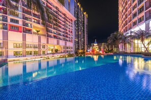 Un hôtel doté d’une piscine, de nombreux balcons et d’une façade bien éclairée la nuit.