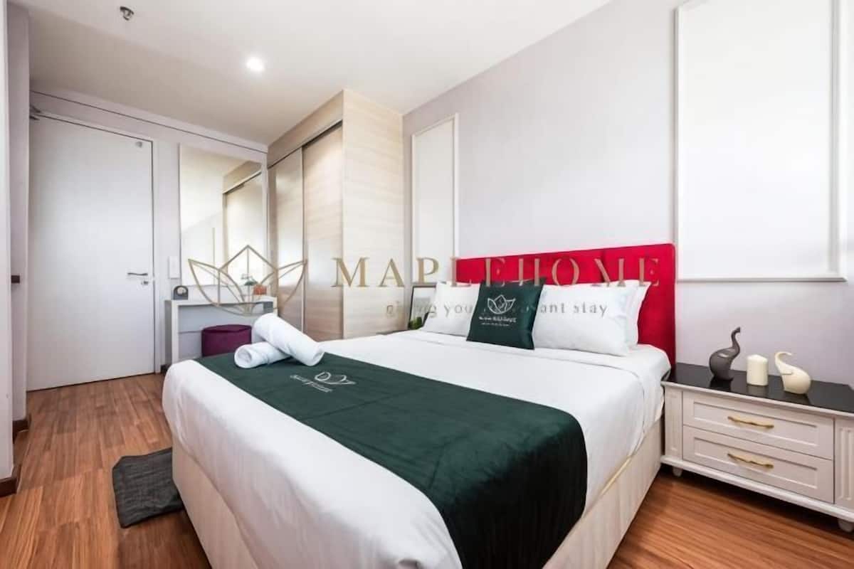 Una habitación de hotel moderna con una cama grande, una mesita de noche, un espejo y un armario.