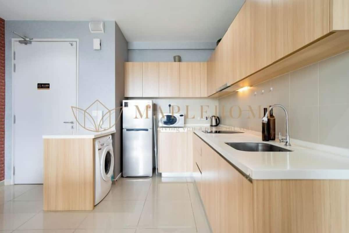 Una cocina moderna con armarios de madera, lavadora integrada y un lavamanos de acero inoxidable.