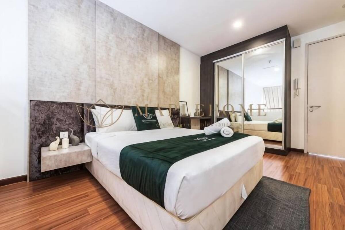Una habitación de hotel moderna con una cama grande, mesitas de noche, un espejo y un armario.