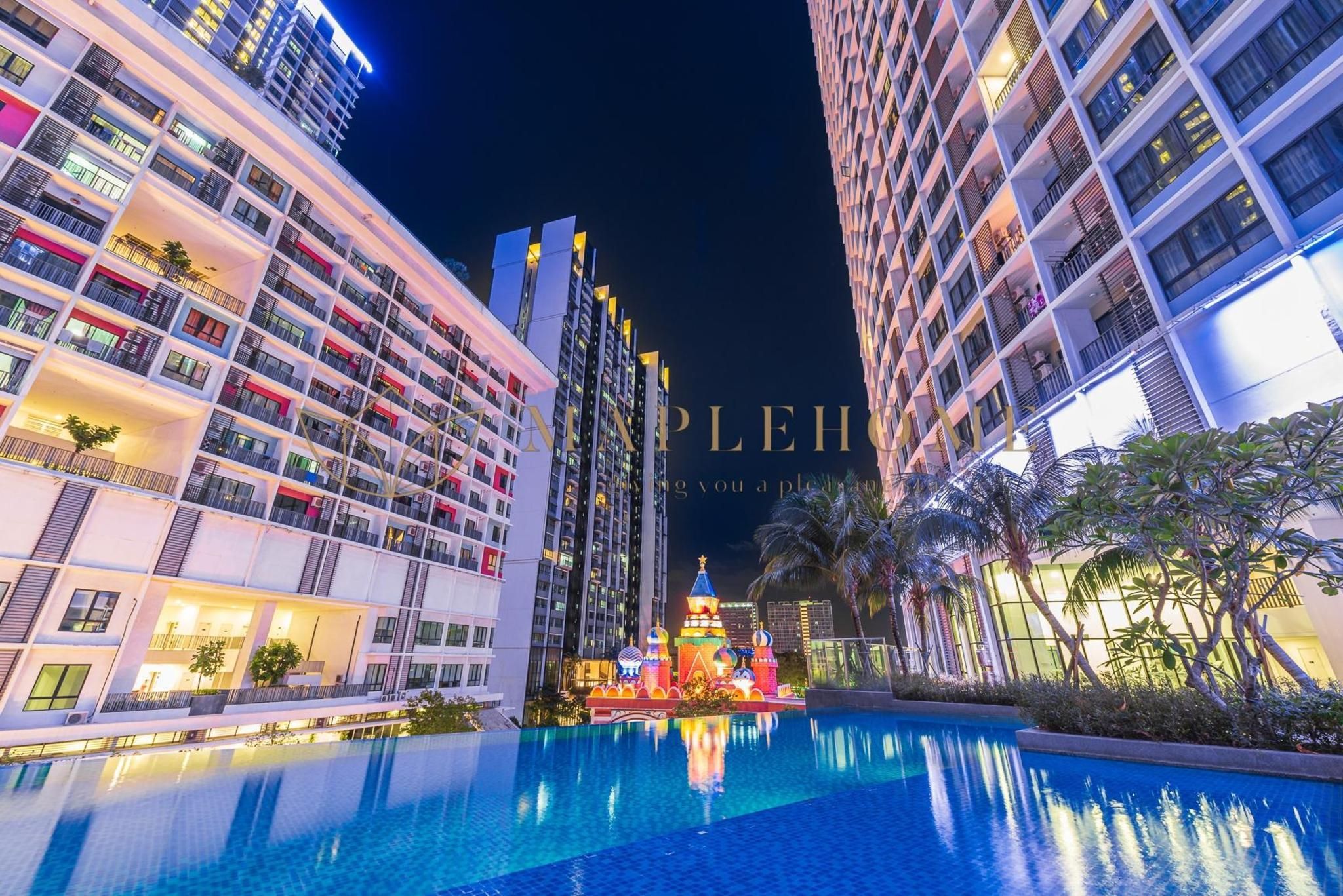 A modern hotel with a large pool, multiple balconies, and a decorative structure in the pool area.