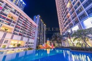Un hôtel moderne doté d’une grande piscine, de nombreux balcons et d’une structure décorative aménagée dans l’espace piscine.