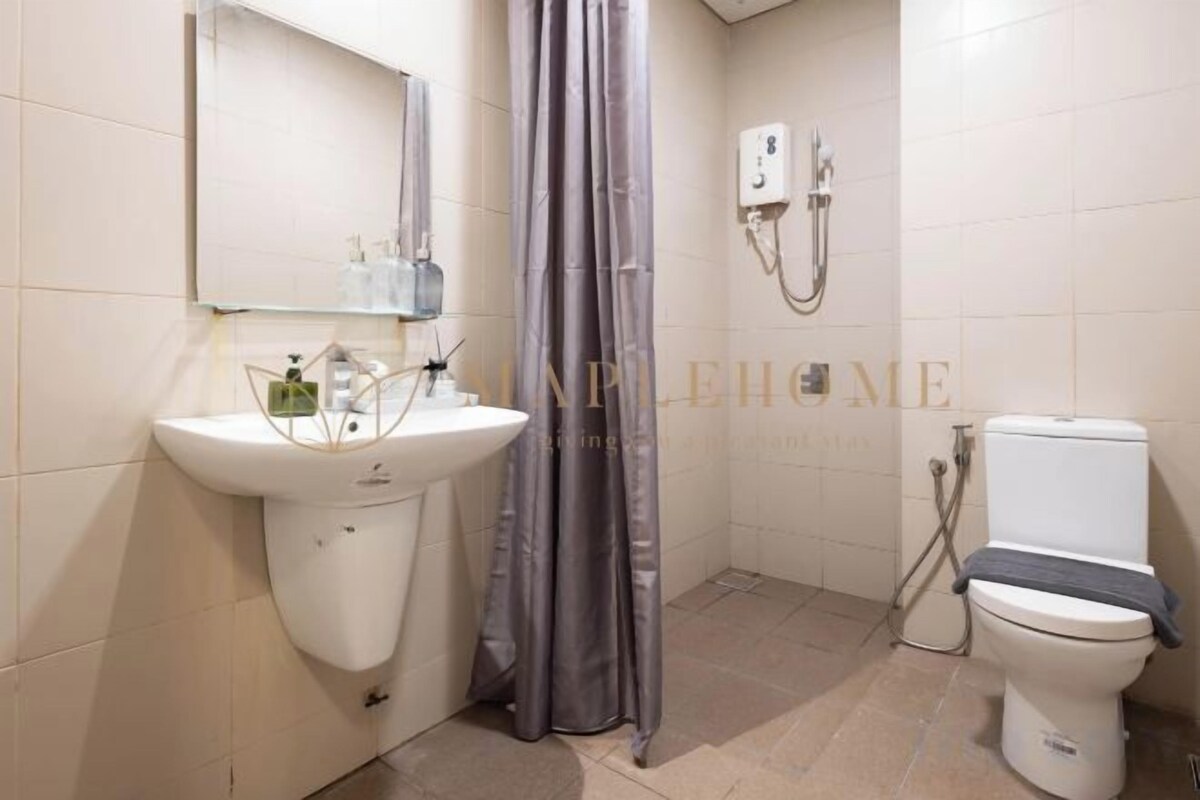 A bathroom with a sink, mirror, shower, and toilet.