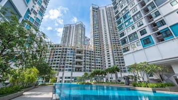 A modern high-rise residential building with a swimming pool in the foreground.