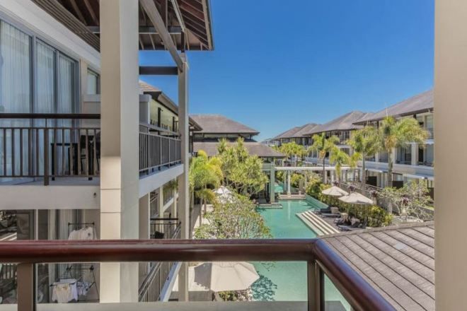 A hotel with multiple floors, a swimming pool, and outdoor umbrellas.