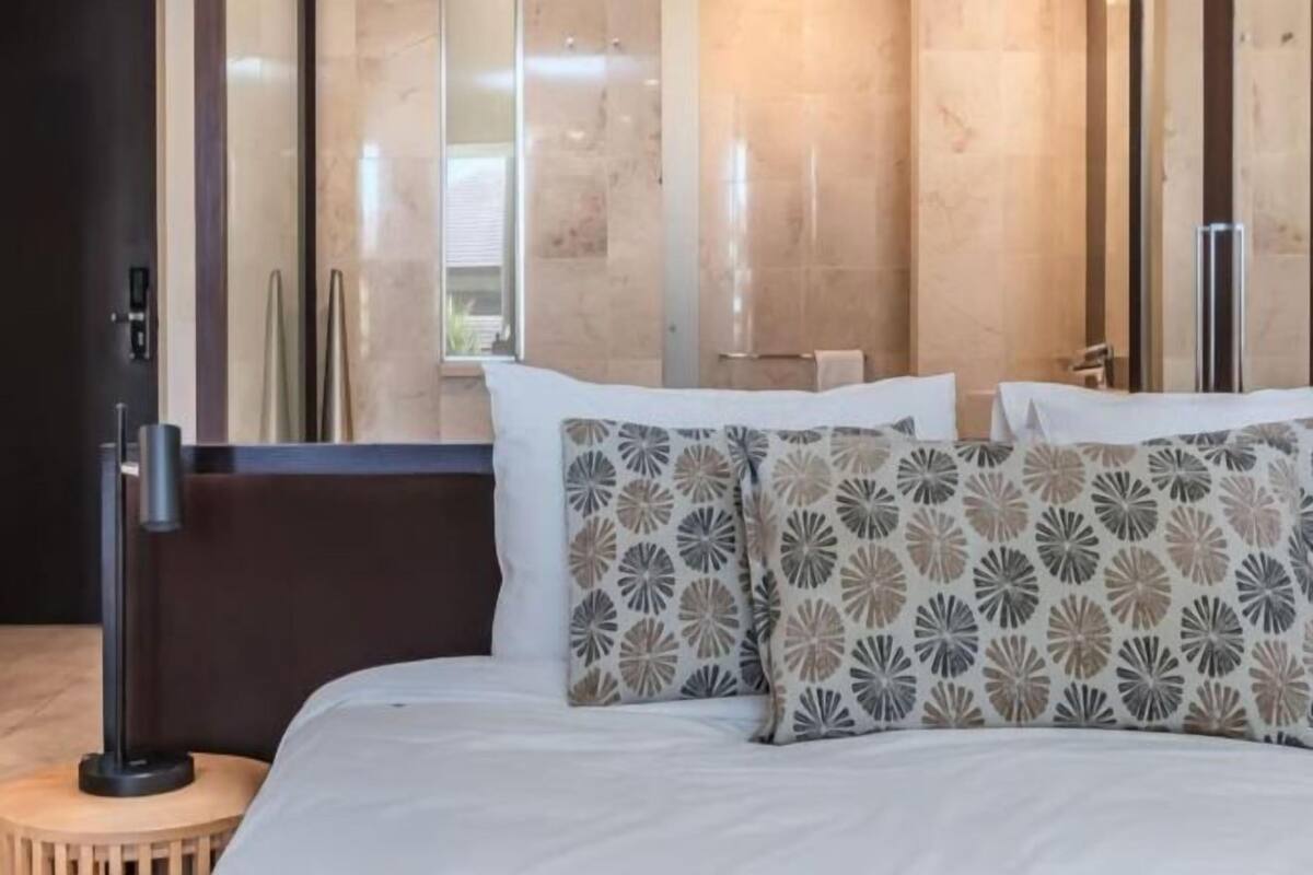 A modern hotel room with a large bed, a bedside table, and a window with a view.