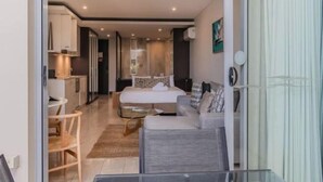 A modern hotel room with a bed, sofa, and a dining area. - Santai Resort - Holiday Management (Casuarina)