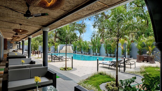 A poolside area with seating, a pool, and surrounding greenery. - Sahaswara Luxury Resort (Anjuna)