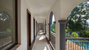 A corridor with a view of a pool and greenery. - Sahaswara Luxury Resort (Anjuna)