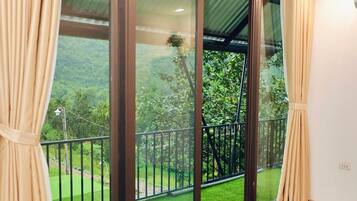 A room with large glass doors leading to a balcony with a green lawn and a metal railing.