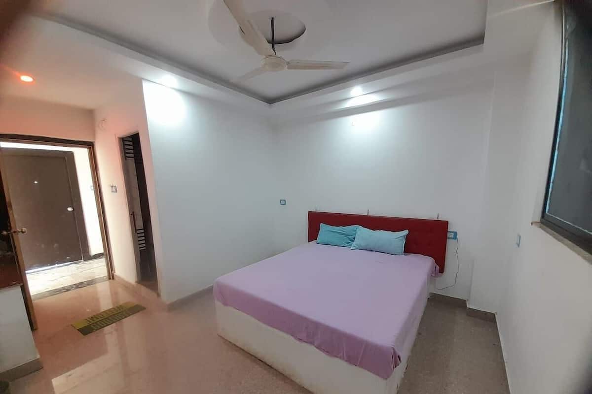 Une chambre à coucher avec un lit, un ventilateur de plafond et une porte donnant sur une autre pièce.