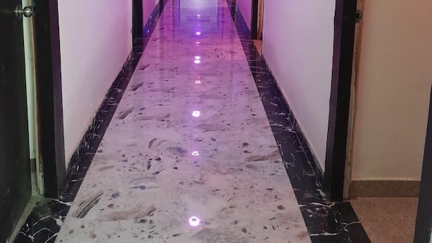 A long, narrow hallway with a marble floor and purple lighting. - Happy Palace Resort (Gaya)