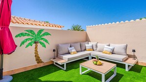 A patio with a white sofa, a wooden coffee table, and a red umbrella. - Mila Moon by Interhome (Callao Salvaje)
