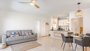 A modern apartment with a grey sofa, a dining area with chairs, a kitchen, and a ceiling fan. - Mila Moon by Interhome (Callao Salvaje)