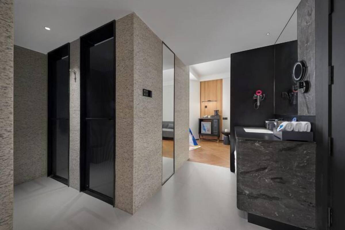 A modern bathroom with a dark marble sink, a mirror, and a towel rack.