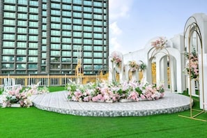 A hotel with a modern building, a circular outdoor area with floral decorations, and a white structure with arches. - Nanyang Changsheng Hotel (Guangzhou)