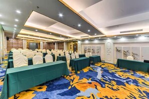 A conference room with rows of tables and chairs, a patterned carpet, and a modern ceiling design.