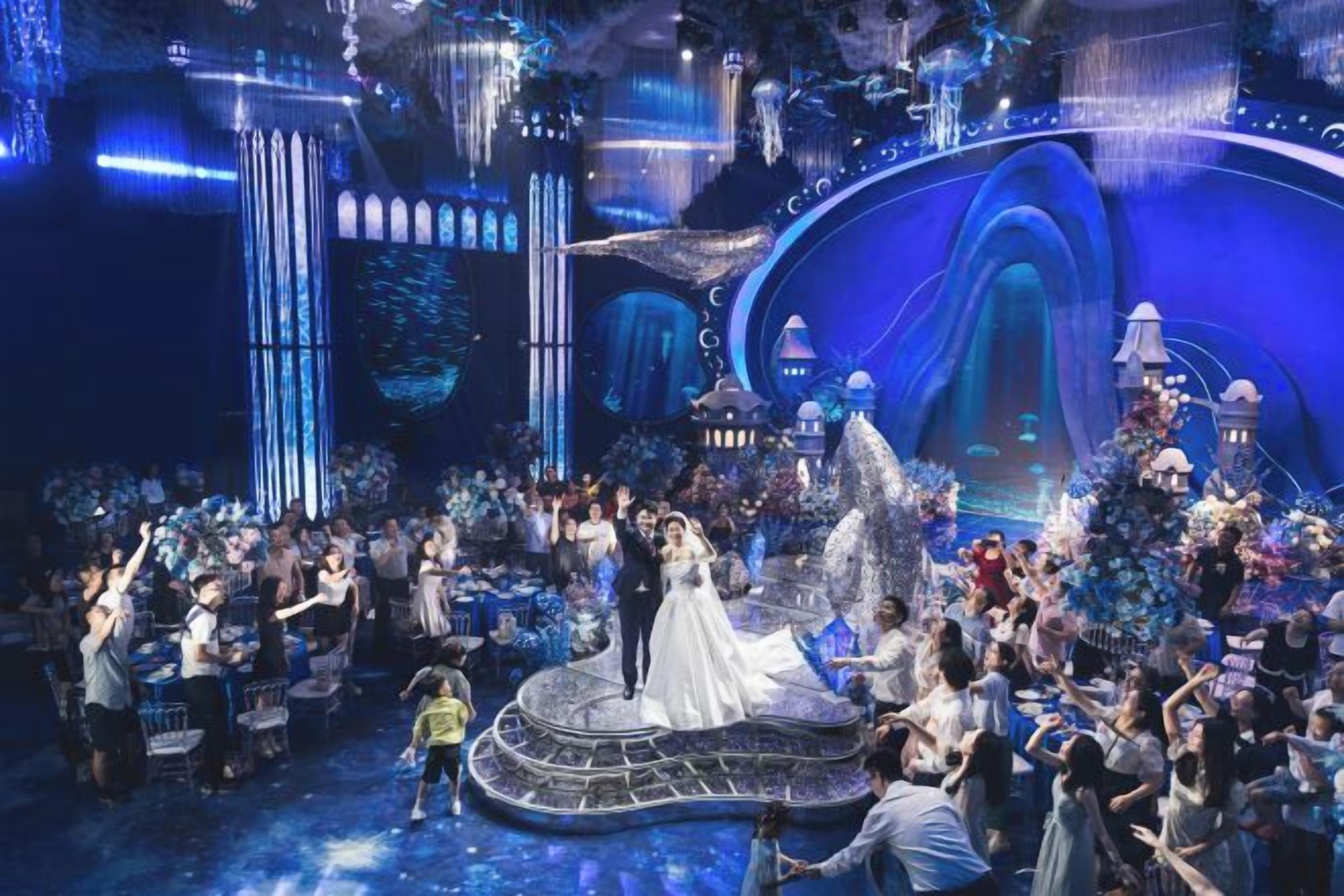 A stage with a crowd, a central figure in a white dress, and a large, ornate backdrop.