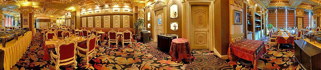 A luxurious hotel lobby with ornate decor, multiple dining areas, and a grand staircase.
