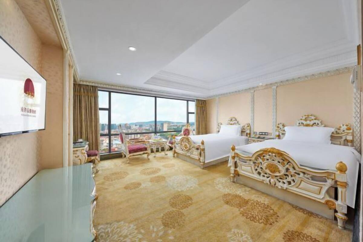 A hotel room with two beds, a large window, and a city view.