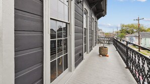 A wooden deck with a railing, large windows, and a potted plant. - Chic 2-bedroom apartment in eclectic Bywater with AC, WiFi (New Orleans)