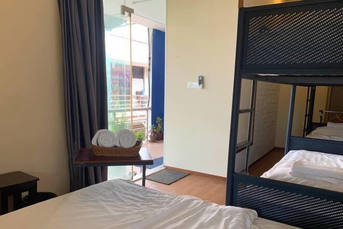 Una habitación de hotel con una litera, una mesita con toallas y vistas al balcón exterior.