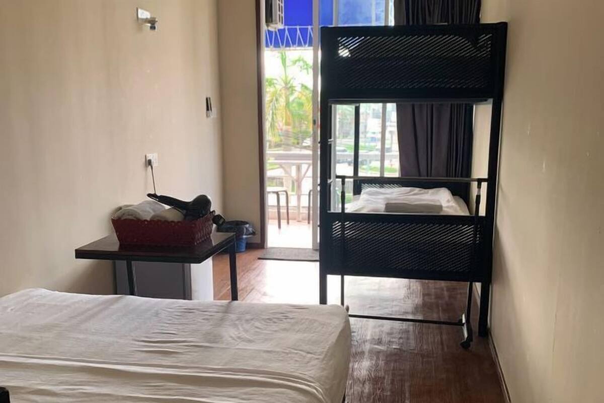 Una habitación con literas, una mesita con una cesta, y vistas al exterior.
