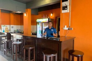 A bar area with a counter, stools, and a refrigerator. - AE Semporna Guesthouse (Semporna)