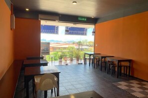 An indoor seating area with tables and chairs, a checkered floor, and a view through a doorway to the outside. - AE Semporna Guesthouse (Semporna)