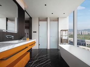 Une salle de bain moderne avec un sol en marbre, un grand miroir et une vue sur le paysage urbain, visible à travers une grande fenêtre.
