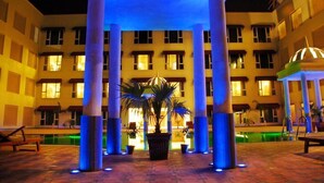 A hotel courtyard with a pool, palm trees, and columns. - The Sky Imperial Jaipur (Amer)