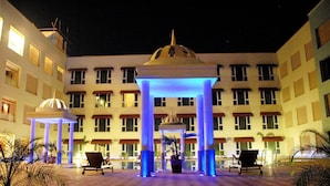 A hotel courtyard with a central dome structure, multiple balconies, and lounge chairs. - The Sky Imperial Jaipur (Amer)