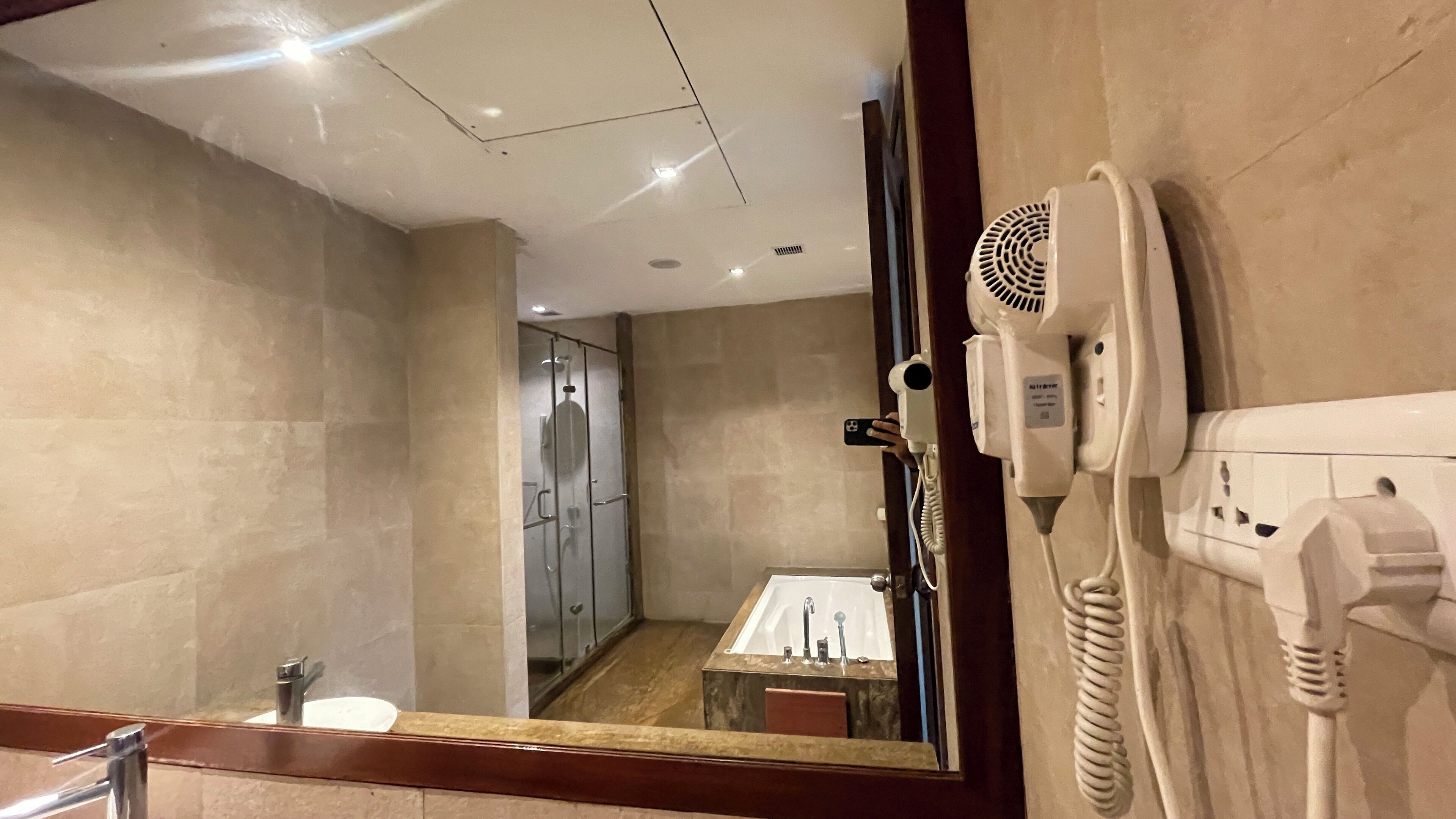 Une salle de bain d’hôtel avec un grand miroir, un sèche-cheveux et un lavabo.