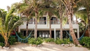 Ein Strandgrundstück mit einem weißen Gebäude, mehreren Balkonen und einer Hängematte im Vordergrund.