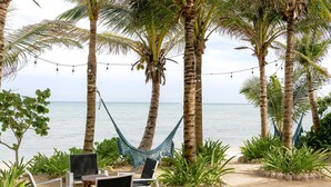 Ein Sitzbereich am Strand mit einer Hängematte, Stühlen und Blick aufs Meer.