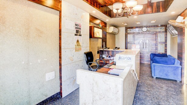 A reception area with a marble counter, a 'No Smoking' sign, a clock, and a blue sofa. - Deep Ganga inn TripandTrip (Puri)