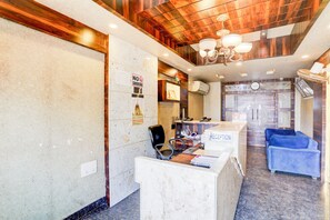 A reception area with a marble counter, a 'No Smoking' sign, a clock, and a blue sofa. - Deep Ganga inn TripandTrip (Puri)