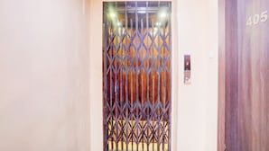 A door with a metal security gate, a digital elevator control panel, and a wooden door with the number 405. - Deep Ganga inn TripandTrip (Puri)