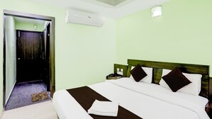 A neatly made bed with a brown headboard, a white pillow, and a folded white towel on the bed. - Deep Ganga inn TripandTrip (Puri)