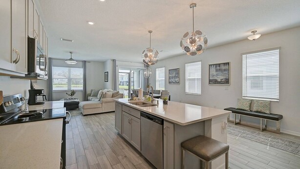 A modern kitchen with a central island, stainless steel appliances, and pendant lighting. - Sienna Sunset: Serene Townhome w/ Pool and Lanai (Sarasota)
