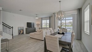 A spacious living room with a dining area, a television, and a staircase. - Sienna Sunset: Serene Townhome w/ Pool and Lanai (Sarasota)