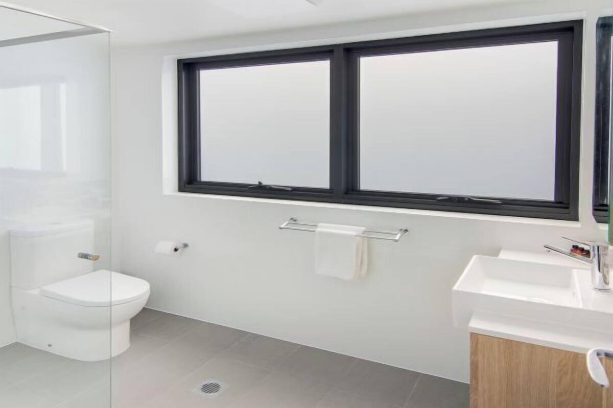 A modern bathroom with a toilet, sink, and window.