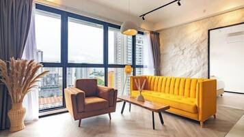 A modern living room with a sofa, armchair, and coffee table, large windows with a city view, and a stone accent wall.