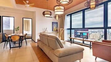 Enjoy the city view from the large window in this stylish living room, featuring a sofa, dining table, and flat-screen TV.