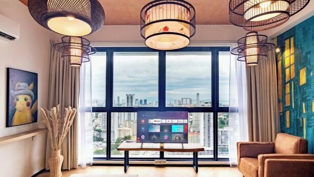 Un soggiorno moderno con vista sulla città, ampie finestre, una TV a schermo piatto e un divano.